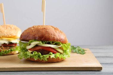 Gri ahşap masada servis edilen lezzetli vejetaryen hamburgerler.