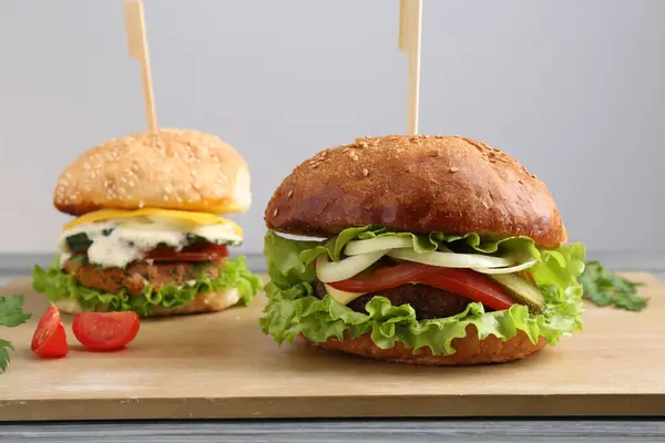 Delicious vegetarian burgers served on grey wooden table