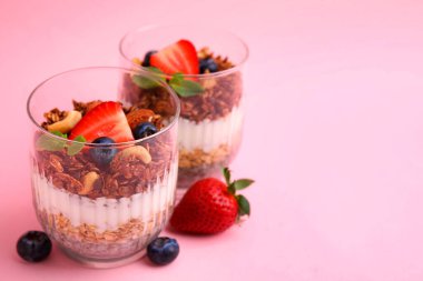 Böğürtlenli, fındıklı, yoğurtlu, pembe arkaplanlı bardakta chia tohumlu, mesaj için yer var.