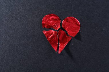 Kırmızıya bulanmış kağıt kalp, siyah arka planda paramparça olmuş. Ayrılma konsepti