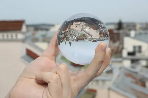 stock image View of beautiful city street, overturned reflection. Man holding crystal ball outdoors, closeup