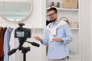 Gülümseyen moda blogcusu evde video kaydederken kıyafetlerini gösteriyor