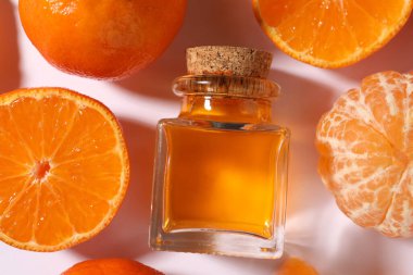 Aromatik mandalina yağı şişede ve turunçgiller beyaz masada, düz yerde.