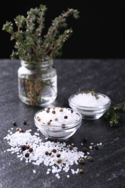 Taze kekikli tuz ve koyu gri desenli masada biber. Yakın plan.