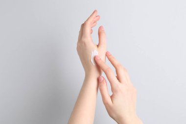 Gri arka plana krem süren kadın, yakın plan.