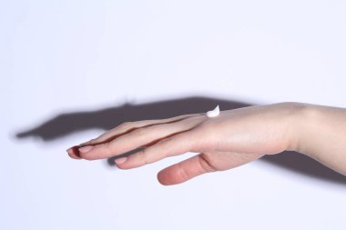 Beyaz arka planda krem sürmüş bir kadın, yakın plan.