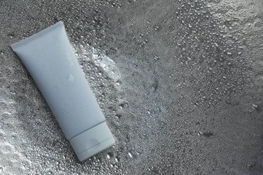 Gümüş arka planda nemlendirici krem, su damlaları, üst manzara. Metin için boşluk