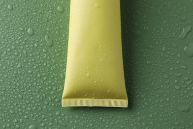 Yeşil zemin üzerinde nemlendirici krem, su damlaları, üst görünüm