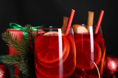 Gözlüklü lezzetli Sangria içkisi ve siyah arka planda Noel süslemeleri, yakın plan.