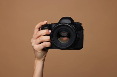 Kahverengi arka planda kamera olan fotoğrafçı, yakın plan