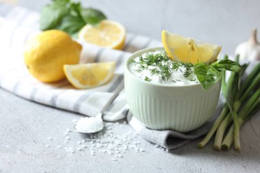 Dereotlu lezzetli yoğurt, yeşil soğan, limon ve tuz açık dokulu masa, yakın çekim.