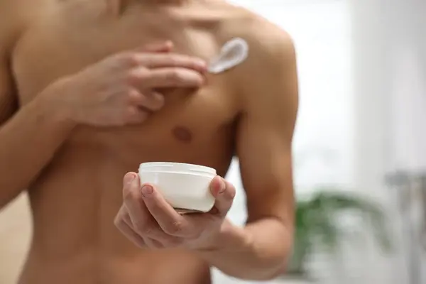 stock image Man applying moisturizing cream onto his shoulder in bathroom, closeup. Space for text