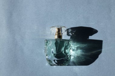 Lüks kadın parfümü. Gri arka planda güneş ışığı şişesi, üst manzara.