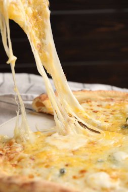 Yemek masasında leziz bir dilim peynirli pizza, yakın plan.