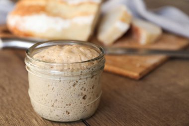 Ekşi ekmek, cam kavanozda, ahşap masada, yakın plan. Metin için boşluk