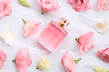 Parfüm ve çiçek dekoru beyaz arka planda, düz yerde.