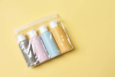 Sarı arka planda plastik çantada kozmetik seyahat seti, üst manzara. Metin için boşluk