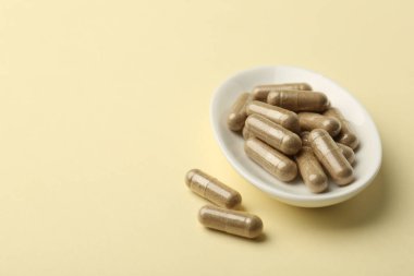 Soluk sarı arkaplan üzerindeki vitamin kapsülleri, metin için boşluk