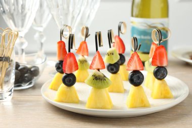 Ananaslı kanepeler, kivi ve böğürtlenler açık ahşap masada, yakın plan.