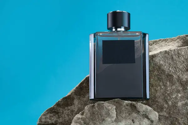 Stylish presentation of luxury men`s perfume on stones against light blue background. Space for text