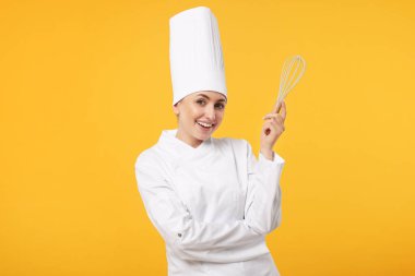 Sarı arka planda çırpı tutan üniformalı mutlu profesyonel pastacı.