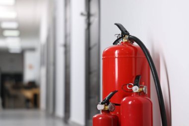 Fire extinguishers in hall, closeup. Space for text clipart