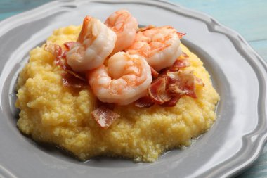 Taze karides, domuz pastırması ve mısır ezmesi tabağı açık mavi ahşap masa, yakın plan.