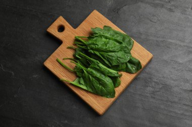 Üzerinde ıslak ıspanak yaprakları olan tahta, koyu dokulu masa, üst görünüm.