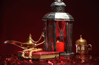 Arapça fener, Kuran, Misbaha ve Aladdin sihirli lamba parlak kırmızı masada.
