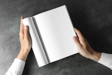 Siyah desenli bir masada elinde boş bir defter tutan adam. Tasarım için model