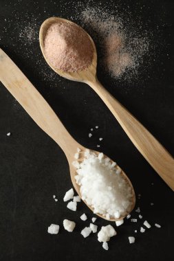 Siyah masadaki kaşıklarda farklı türde organik tuz, düz.