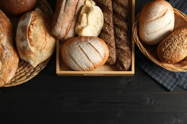 Siyah ahşap masanın üzerinde farklı türde taze ekmek bulunan sepetler, düz. Metin için boşluk