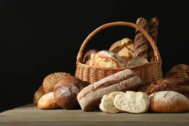 Ahşap masa üzerinde taze ekmek farklı tipleri ile hasır sepet