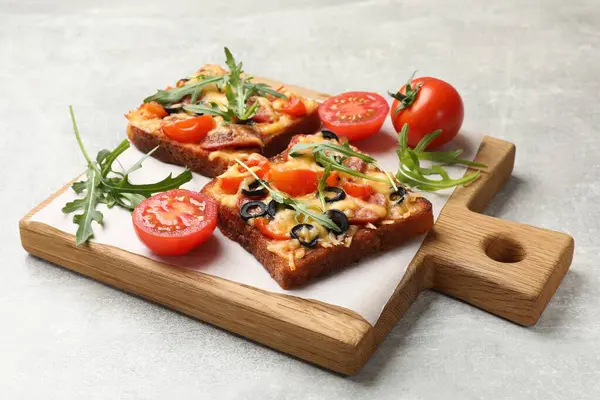 Tasty pizza toasts, fresh tomatoes and parsley on grey table