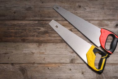 Ahşap zemin üzerinde renkli saplı testereler, düz yatıyordu. Metin için boşluk