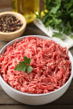 Tabakta çiğ et, maydanoz, baharat ve yağ, ahşap masa, yakın plan.
