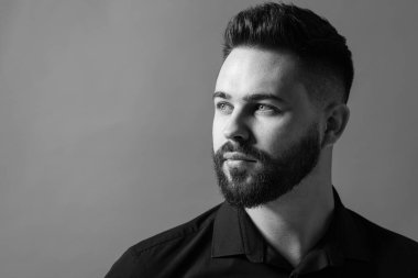 Gri arka planda yakışıklı sakallı adamın portresi, mesaj için yer var. Siyah ve beyaz etkisi