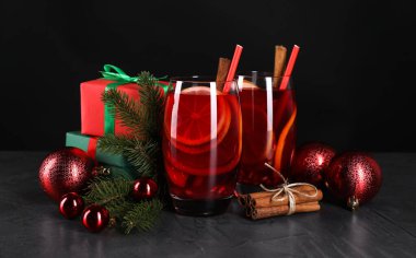 Lezzetli Sangria kadehleri ve Noel süslemeleri koyu dokulu masada, yakın plan.