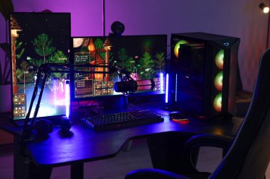 Video oyunları oynuyorum. Modern bilgisayar ve neon lambalı oyun koltuğu olan şık bir oda.