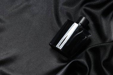 Şatafatlı erkek parfümü şişede, siyah saten kumaşla, üst tarafta. Metin için boşluk