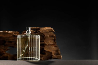 Şatafatlı erkek parfümü gri masada, koyu arka planda, mesaj için yer var.