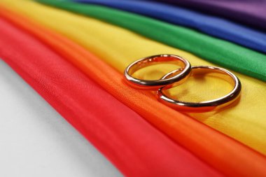 Gökkuşağı LGBT bayrağı ve pembe arka planda alyanslar, yakın plan.