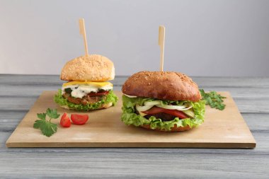 Gri ahşap masada servis edilen lezzetli vejetaryen hamburgerler.