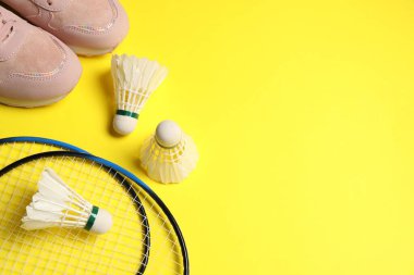 Sarı arka planda badminton mekikleri, raketler ve spor ayakkabıları var. Metin için boşluk