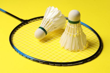 Tüylü badminton mekikleri ve sarı arka planda raket, yakın plan