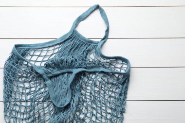 Beyaz ahşap masada mavi iplik çantası, üst manzara.