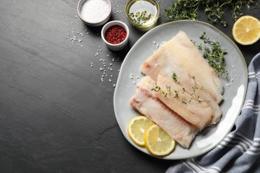 Çiğ morina balığı, mikroyeşillik, baharat ve limonlu tabak koyu dokulu masa, düz yatak. Metin için boşluk