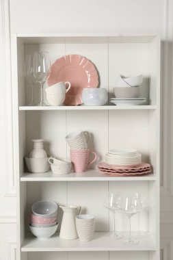Farklı seramik bulaşık takımları ve dolaptaki raflarda bulunan bardaklar.