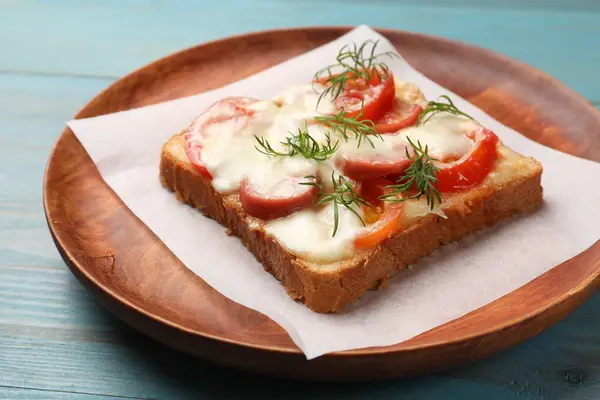 Tasty pizza toast with cheese, tomato and dill on light blue wooden table, closeup