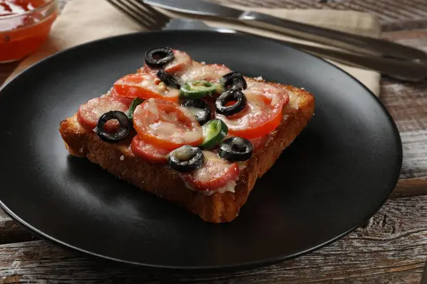 Tasty pizza toast and cutlery on wooden table, closeup